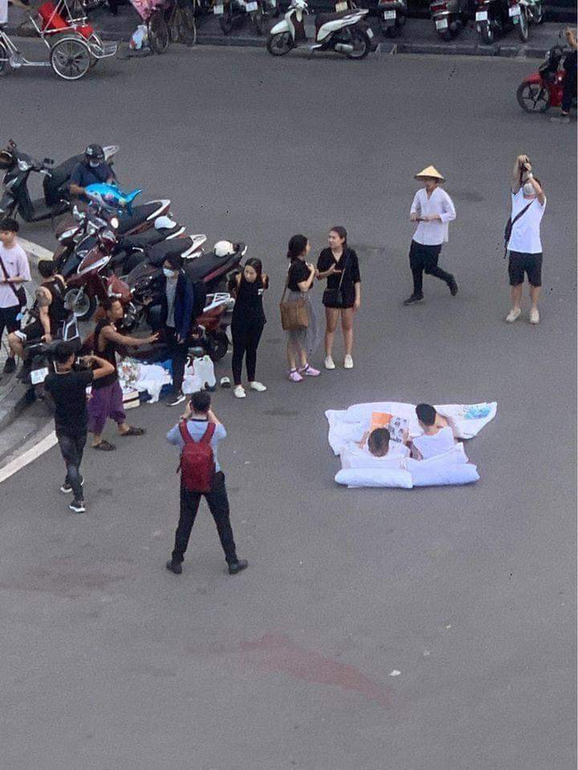 Chuyện lạ nhất phố Hà Nội hôm nay: Đôi bạn trẻ bày gối, trải chăn nằm đọc sách ngay giữa quảng trường bất chấp xe cộ qua lại khiến dân mạng cực kỳ tranh cãi - Ảnh 2